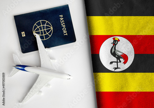 Flag of Uganda with passport and toy airplane. Flight travel concept