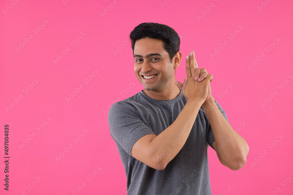 Portrait of a happy young man making shooting gesture by his hands Portrait of a happy young man making shooting gesture by his hands
