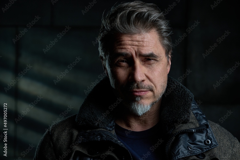 Portrait of confident casual middle aged, mid adult caucasian man in his 50s, smiling, standing against dark gray wall. . Copy space . Portrait of confident casual middle aged, mid adult caucasian man in his 50s, smiling, standing against dark gray wall. . Copy space .