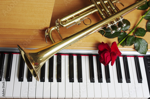 Fotografie Red rose and trumpet on the piano keyboard.