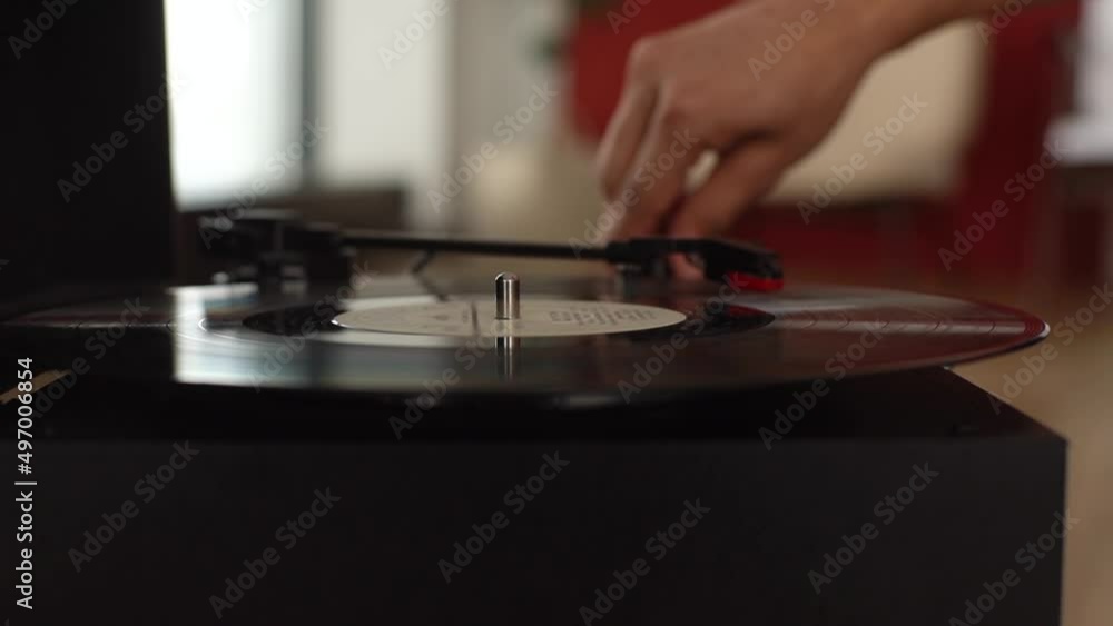 Close-up hands of unrecognizable man adjusting head old record player and vinyl discs at home. Music lover listening to classical music. Closeup of turning on turntable and placing needle on record. Close-up hands of unrecognizable man adjusting head old record player and vinyl discs at home. Music lover listening to classical music. Closeup of turning on turntable and placing needle on record.