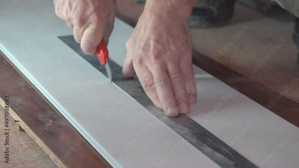 A man cuts a plastic pvc panel with a construction knife A man cuts a plastic pvc panel with a construction knife