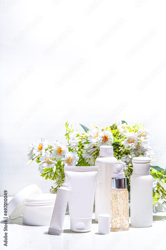 Foraged and wild-harvested beauty, Cosmetic skincare products on white background with wild grown flowers. Set white jars, tubes, droppers, bottles. Spa, daily organic natural skin care routine