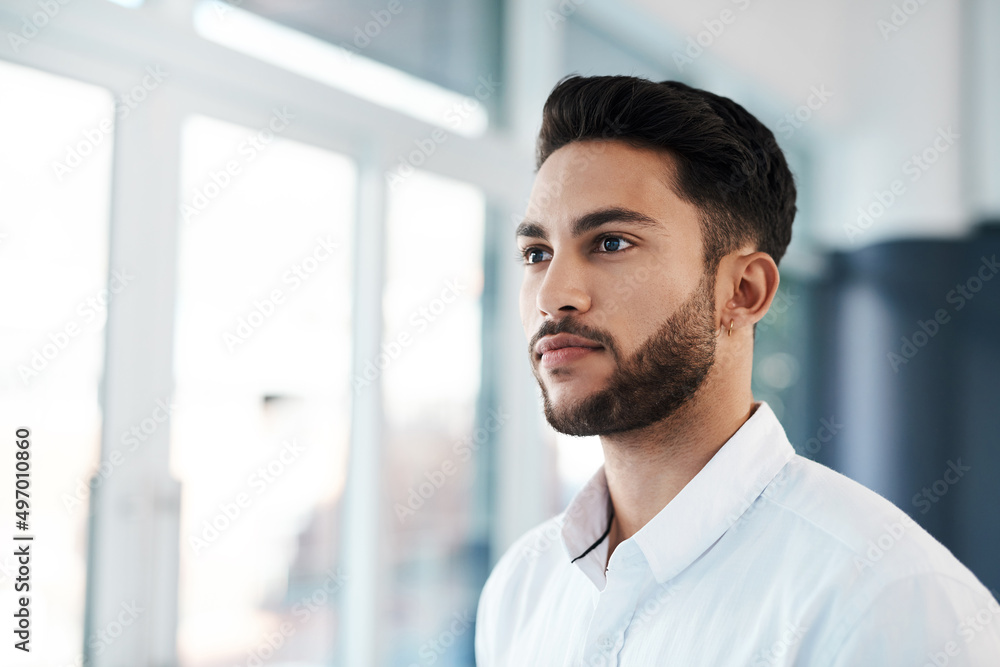 Believing it before I see it. Cropped shot of a handsome young businessman looking contemplative while standing in his office alone. Believing it before I see it. Cropped shot of a handsome young businessman looking contemplative while standing in his office alone.