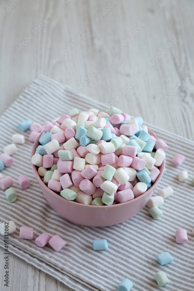 Obraz premium Rainbow Fruity Mini Marshmallows in a Pink Bowl, side view. Copy space.