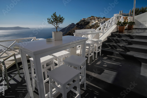 Breathtaking view from an outdoor bar with chairs and tables in Fira Santorini