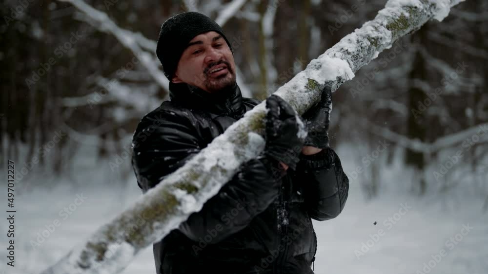 strong man is lifting log in winter forest, training alone in nature, keeping fit strong man is lifting log in winter forest, training alone in nature, keeping fit