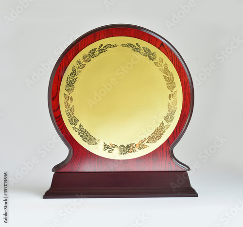 Front view of a wooden trophy or plaque with blank golden plate for the text or logo placement. Winner trophy with empty plaque on white background.