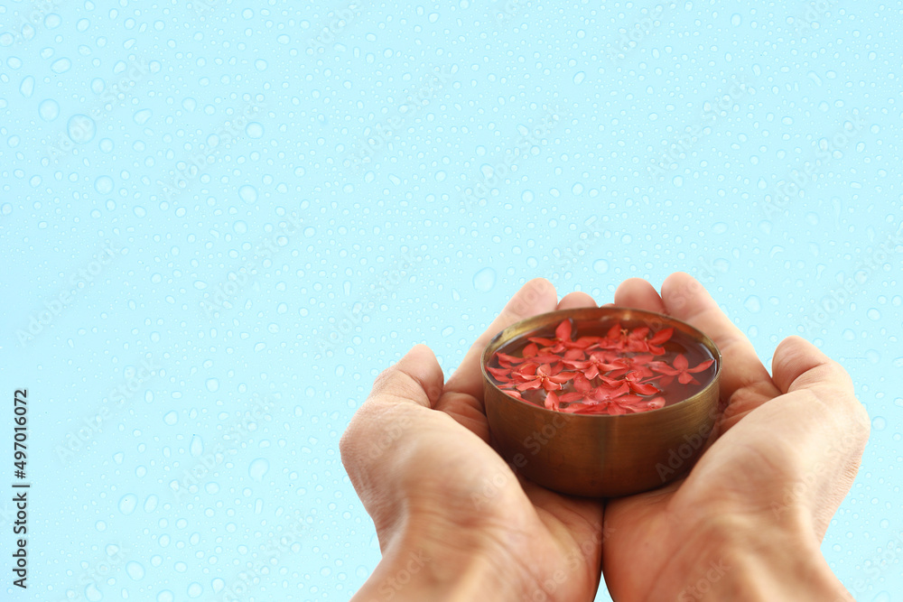 Hand hold bowl of water against blue background with water drop for Songkran day - Thai traditional culture Hand hold bowl of water against blue background with water drop for Songkran day - Thai traditional culture