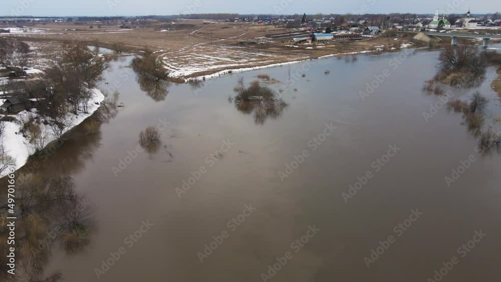 A gloomy river stream with gray water, the remains of snowdrifts on the shore. Spring, snow melts, dry grass, flood and river flood. Day, cloudy weather, soft warm light. UHD 4K A gloomy river stream with gray water, the remains of snowdrifts on the shore. Spring, snow melts, dry grass, flood and river flood. Day, cloudy weather, soft warm light. UHD 4K