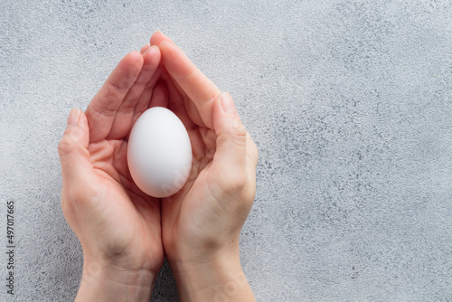 Human hands holding a white egg