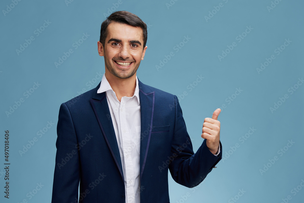 smiling man in a blue business suit showing thumb up on a blue isolated ...