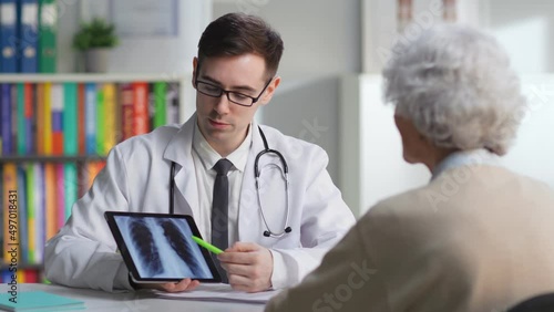 Radiologist discuss x-ray with aged patient in medical center photo