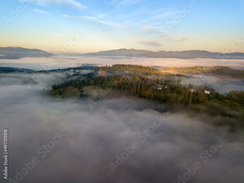 The rays of dawn over the fog in the Ukrainian Carpathians. Aerial drone view. © Sergey