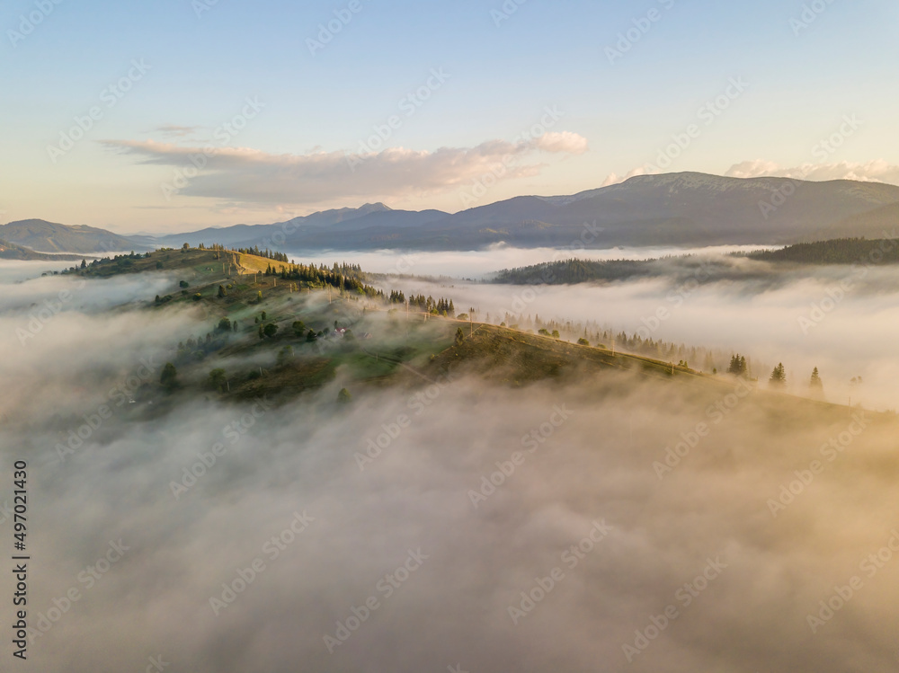 Mountain settlement in the Ukrainian Carpathians in the morning mist. Aerial drone view.