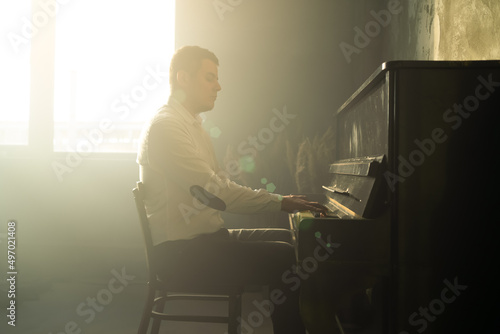 Composer man play on the old piano. Keyboards. Performance on the concert. Musician plays. Cinematic photo with smoke.