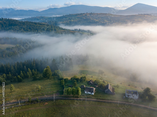 Mountain settlement in the Ukrainian Carpathians in the morning mist. Aerial drone view.