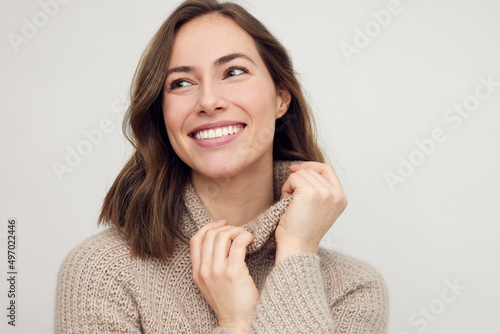 Portrait of young happy woman smiling on white background while looking left. Big smile on her face, looking beautiful, natural and charming.	