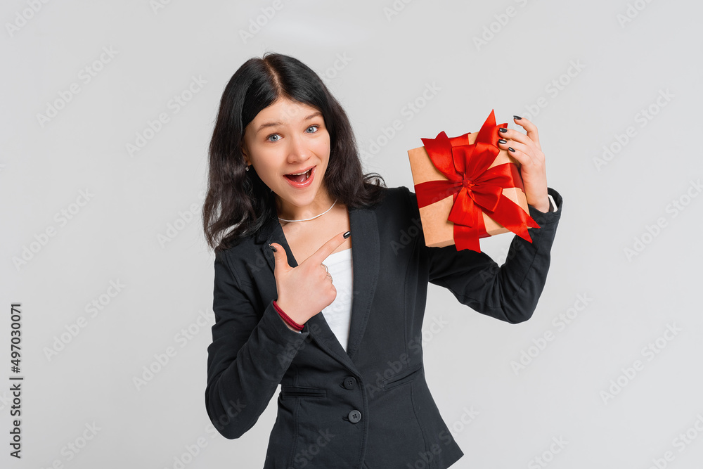 Curious cute brunette teenager girl in black blazer celebrating birthday, wonder whats inside b-day gift, shaking box and smiling happy, white background. Holidays, celebration and birthday concept Curious cute brunette teenager girl in black blazer celebrating birthday, wonder whats inside b-day gift, shaking box and smiling happy, white background. Holidays, celebration and birthday concept