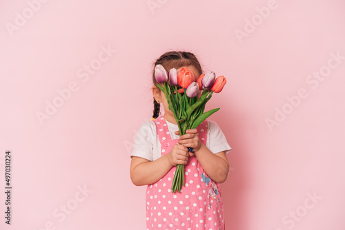 Little girl with bouquet of tulips against pink background. happy mother's day