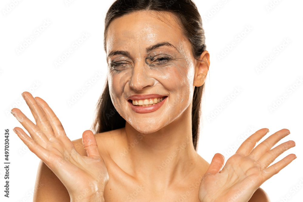 Portrait of a smiling woman with smeared makeup removing lotion on her face. in a white background Portrait of a smiling woman with smeared makeup removing lotion on her face. in a white background