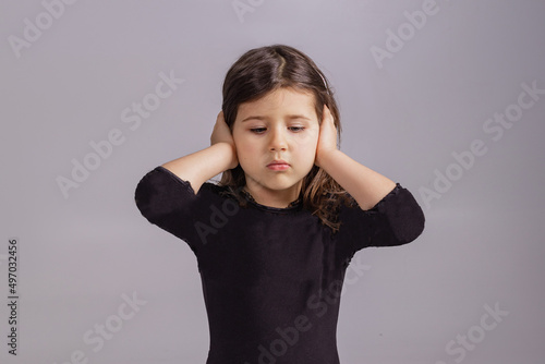 The little girl covered her ears with her hands and does not want to listen to anyone. Portrait of a naughty child 4 years old
