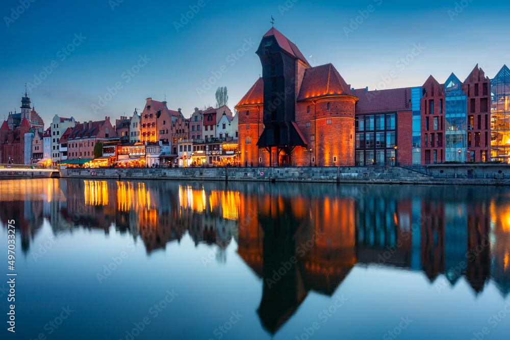 Naklejka premium Historic port crane in Gdansk reflected in the Motlawa river at dusk, Poland