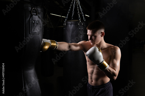 Boxer the blows The practices athlete bag glove black young male body, from strong gloves from sport for fist guy, sportswear aggression. Athletic model box, fitness
