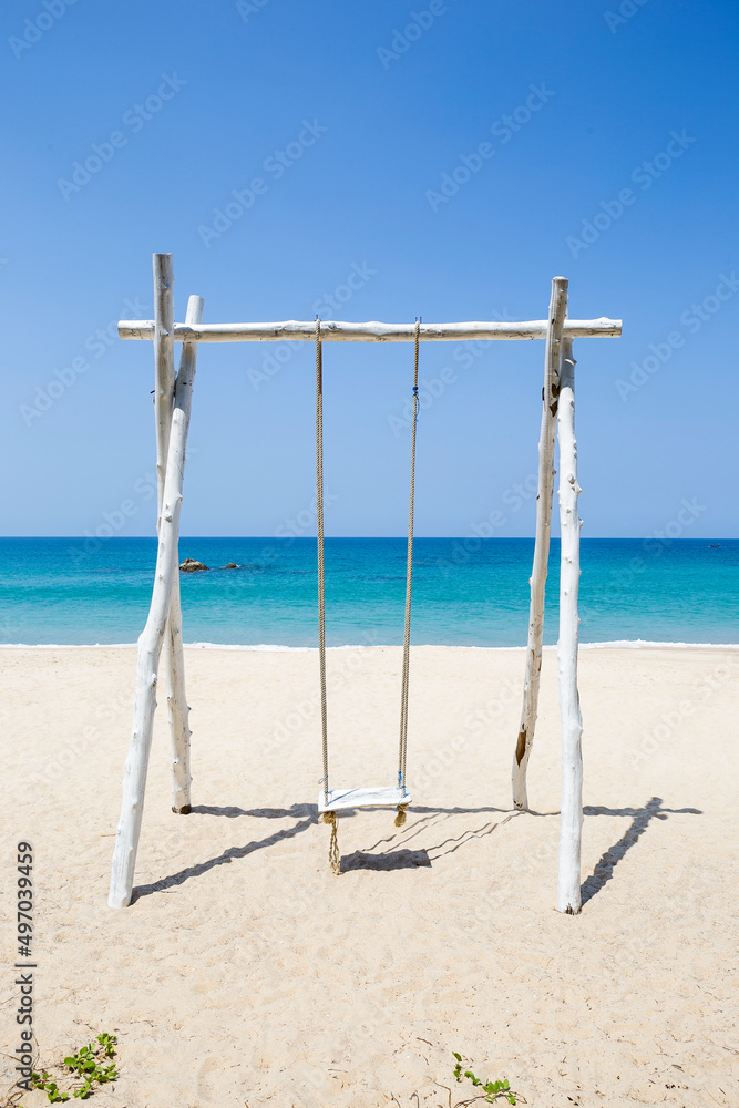 Wooden swing on peaceful beach background, relax by the sea, summer holiday destination, vertical style Wooden swing on peaceful beach background, relax by the sea, summer holiday destination, vertical style