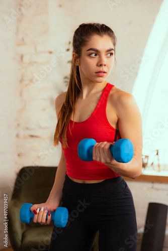 Close-up portrait of young pretty girl training with sport equipment at home, indoors. Concept of sport, fitness, aerobic, sporty lifestyle.
