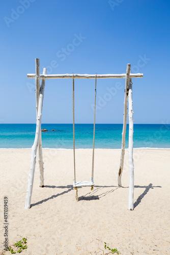 Wooden swing on peaceful beach background, relax by the sea, summer holiday destination, vertical style