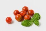 Cherry tomatoes with green basil on white background.