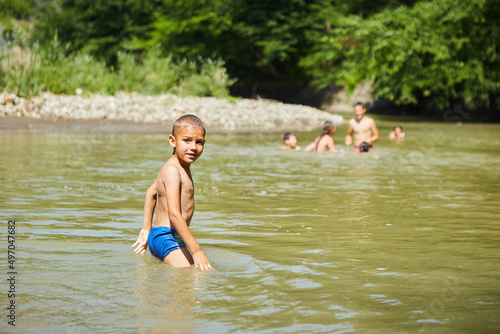 A boy is bathing in yellow river water. Rural recreation.