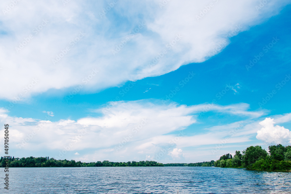 landscape with lake and white clouds on blue sky. Summer landscape.