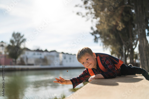 Cute small boy playing with a small ball by the river