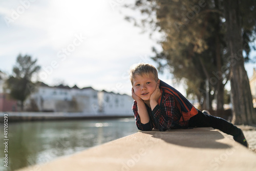 Portrait of sweet small boy relaxing on the riverbank