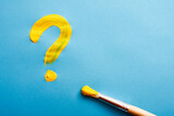 Yellow question mark written with oil paint on blue.