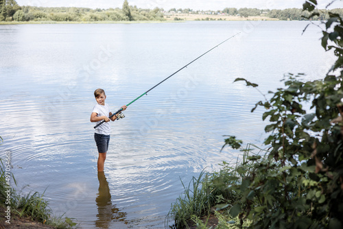 Teenager boy fishing with rods in calm river. Slow life in countryside.