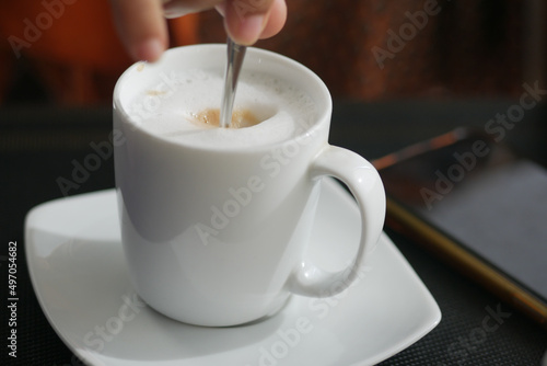 person hand stirring coffee with spoon.