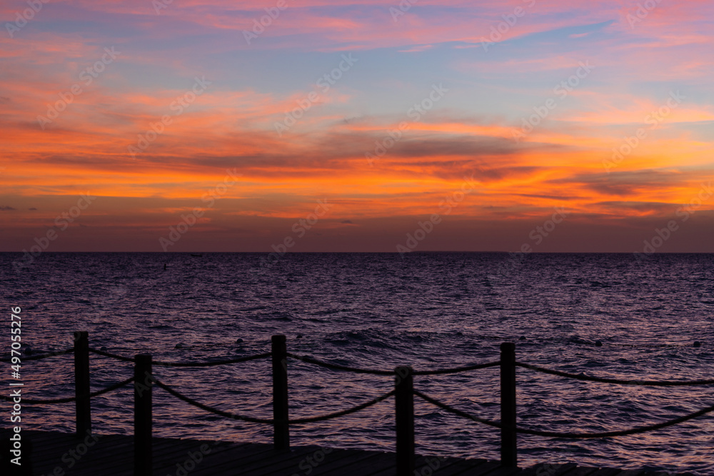 Rope bridge silhouette at sunset. Beautiful seascape, bright orange sky and sea