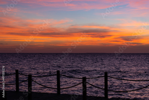 Rope bridge silhouette at sunset. Beautiful seascape, bright orange sky and sea