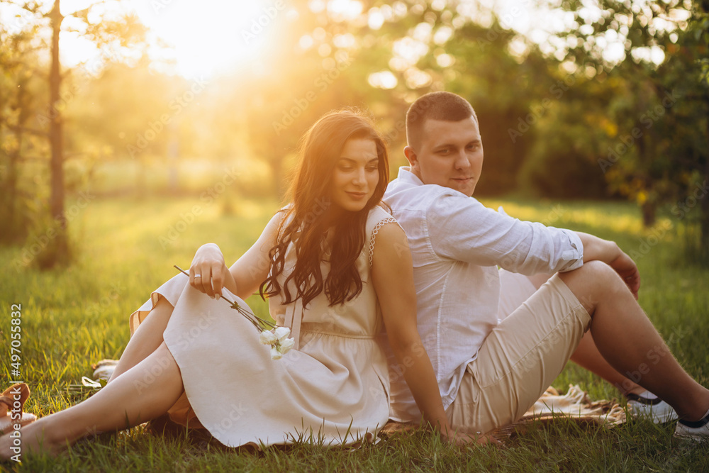 A romantic couple is relaxing while sitting on the grass and looking at faces of each other. A romantic couple is relaxing while sitting on the grass and looking at faces of each other.