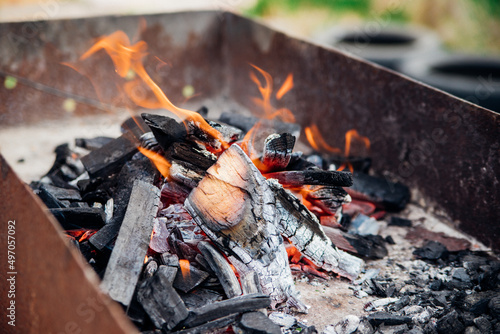 A brightly burning bonfire with a red flame made from wood in an outdoor grill.An adventurous lifestyle in travel. Active weekend recreation in the wild outdoors.