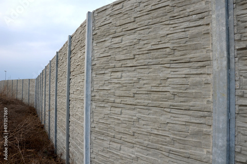 soundproof wall made of concrete porous ribbed material. fence of gray blocks embedded in metal beams, on street. road traffic noise garden and residential area. protection of Jerusalem, rocket