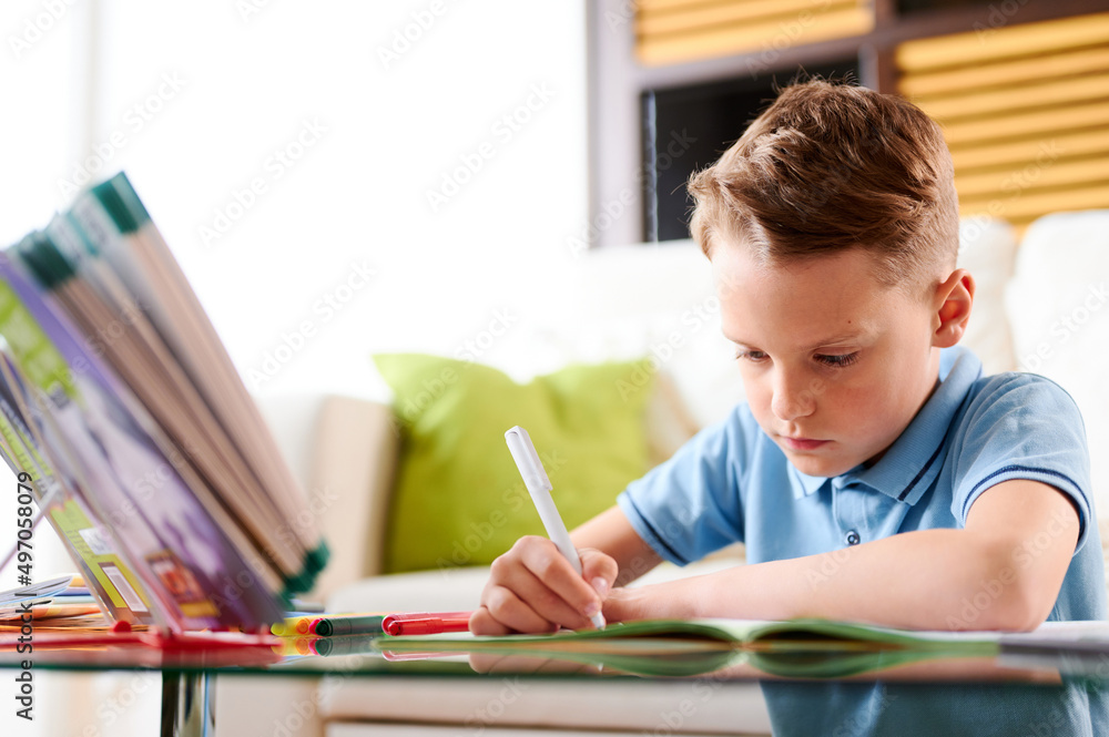 Caucasian Schoolboy at his desk doing his maths homework. Home schooling or Distance learning Caucasian Schoolboy at his desk doing his maths homework. Home schooling or Distance learning