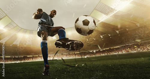 Professional soccer player in action at the stadium with flashlights hitting the ball for the winning goal, wide angle. Concept of sport, competition, movement, overcoming.