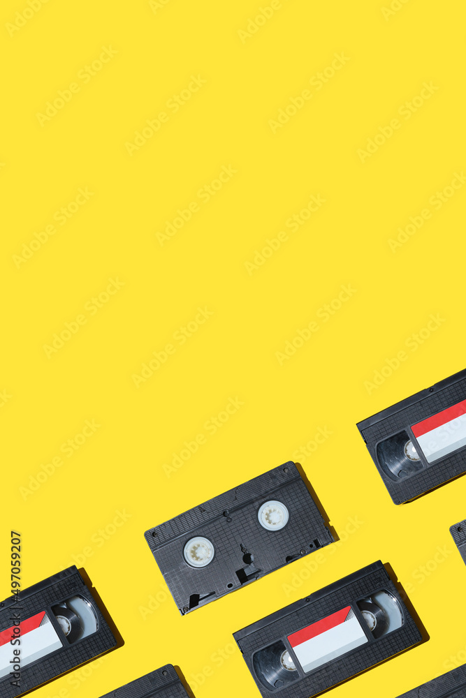 VHS video cassette, Old black videotape pattern on a yellow background, Outdated technology background. VHS video cassette, Old black videotape pattern on a yellow background, Outdated technology background.