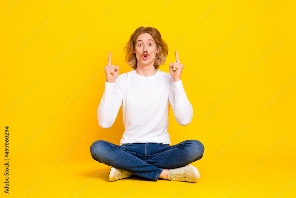 Photo of attractive impressed guy wear white shirt pointing fingers up empty space isolated yellow color background Photo of attractive impressed guy wear white shirt pointing fingers up empty space isolated yellow color background