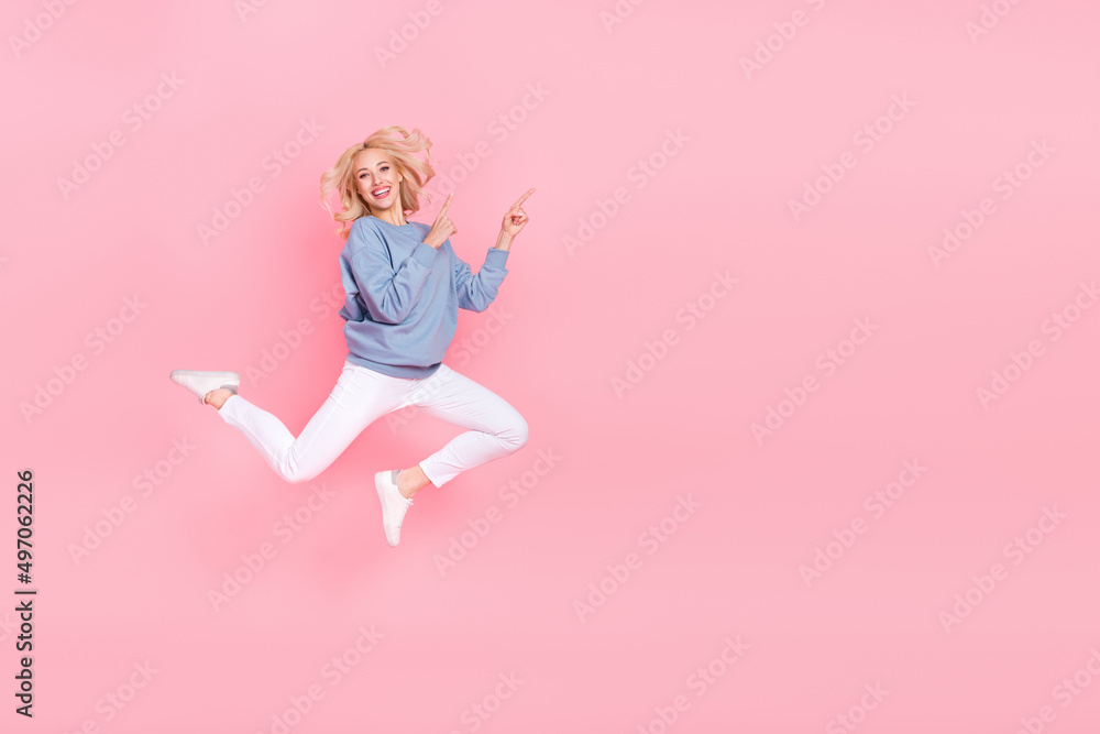 Fototapeta premium Full size photo of young cheerful lady promoter jump indicate fingers empty space promo select isolated over pink color background