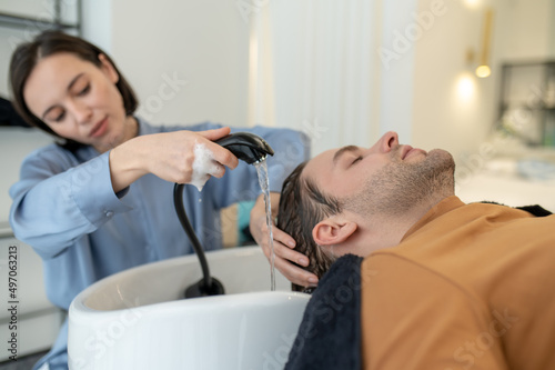Hairdresser washing hair to the male client in a beauty salon